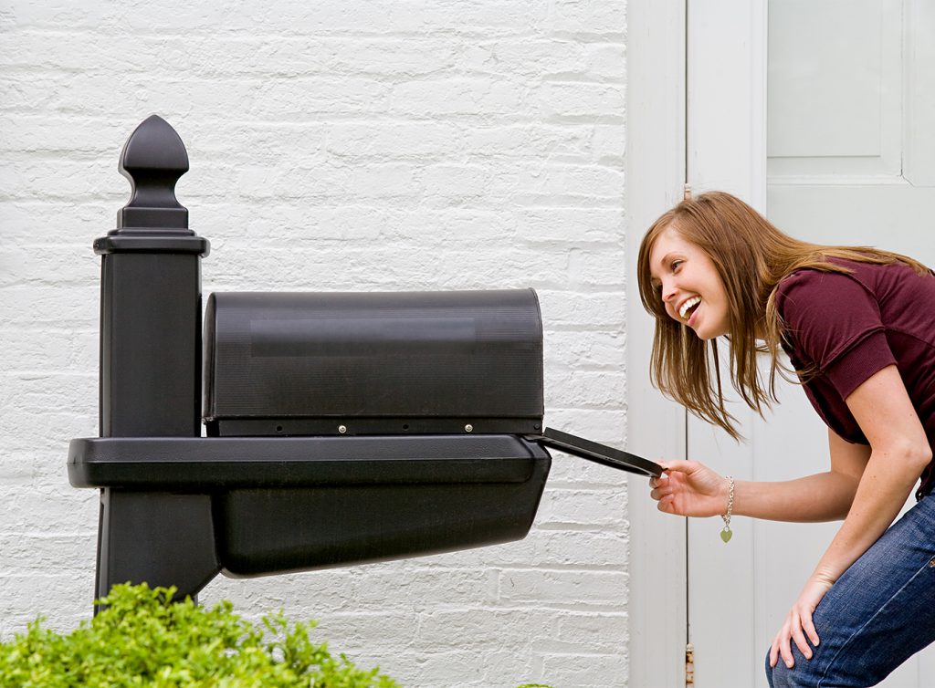 A young woman looking inside a mailbox