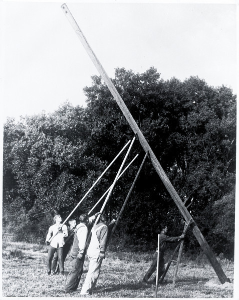 Original REA employees setting a pole by hand - photo in black and white