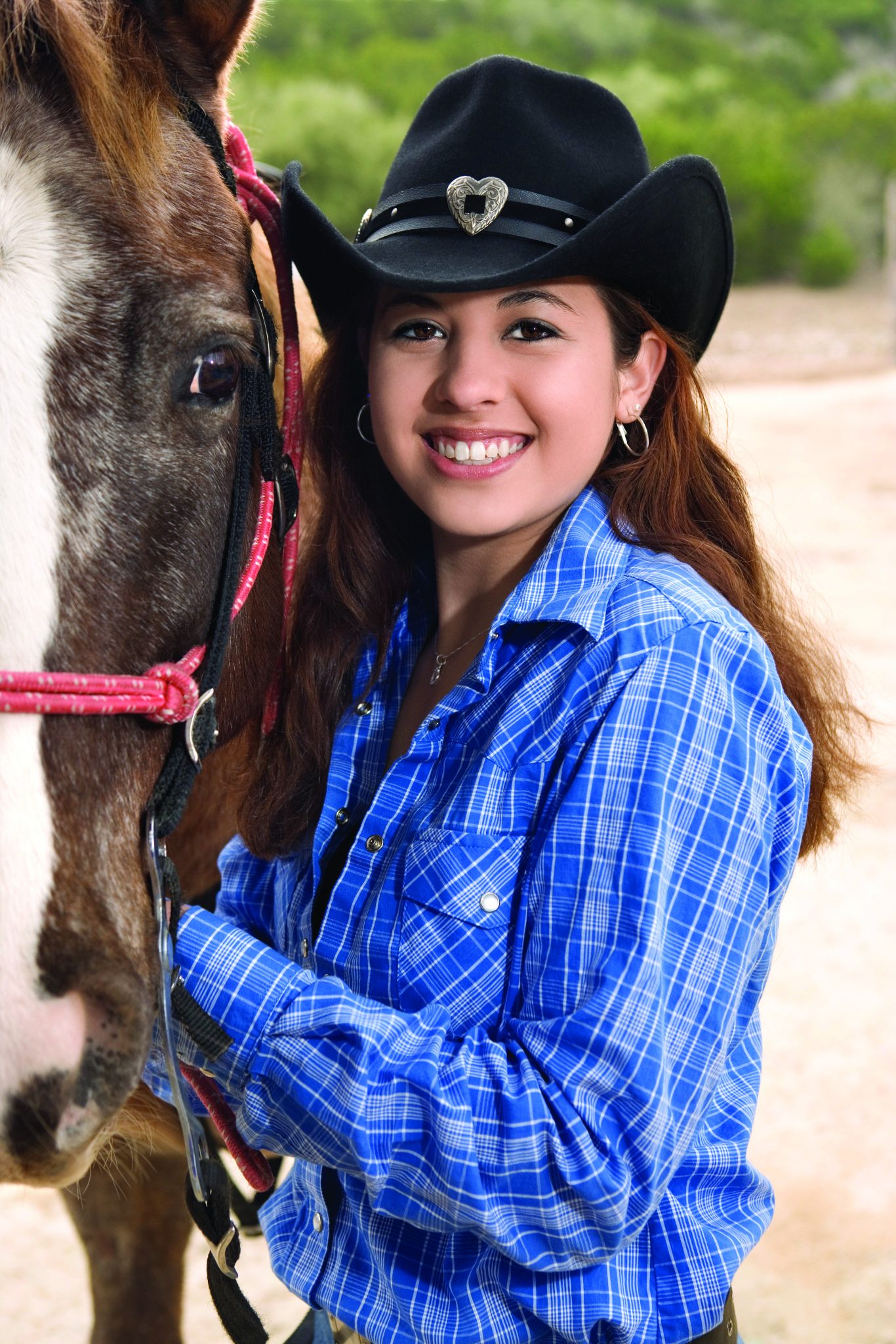 Teenage girl wearing a western hat with her horse