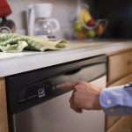 A hand pushes the start button on an Energy Star dishwasher