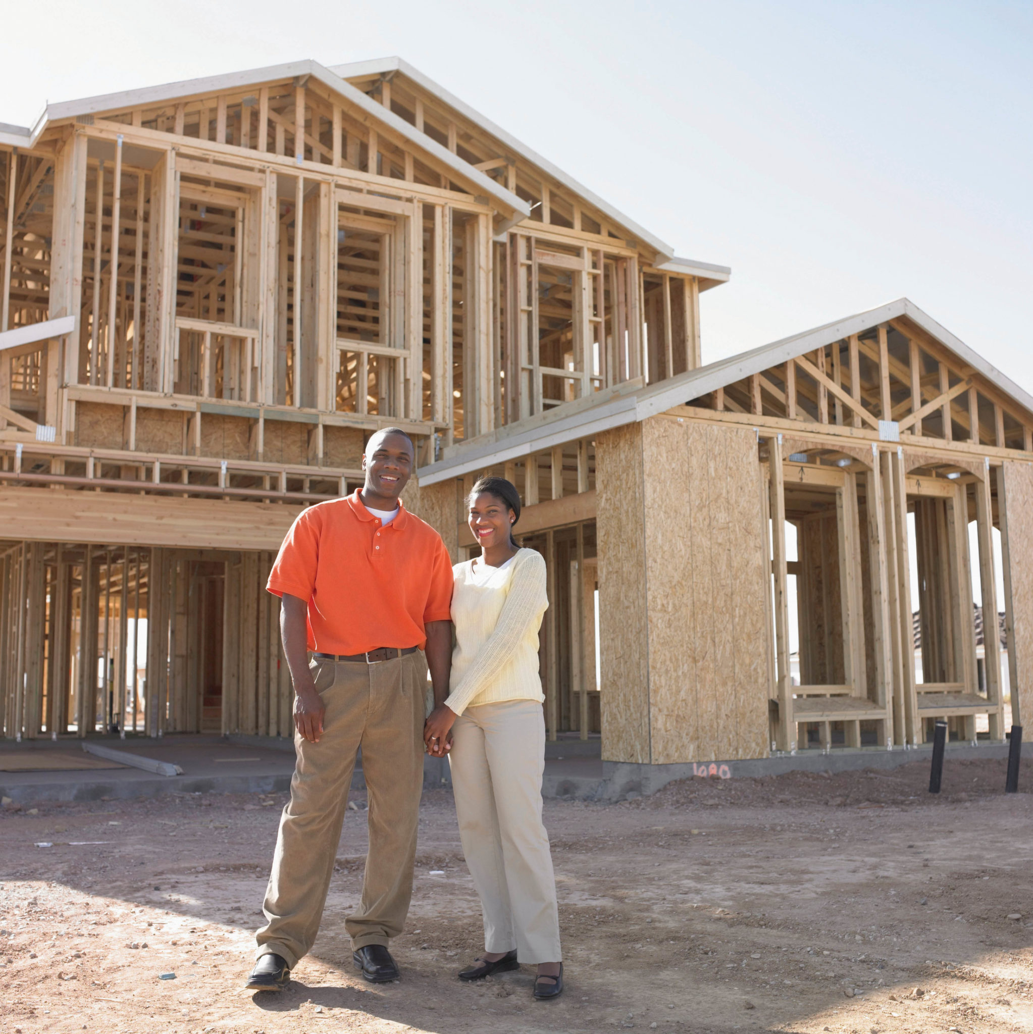 A couple stands in front of a home being constructed