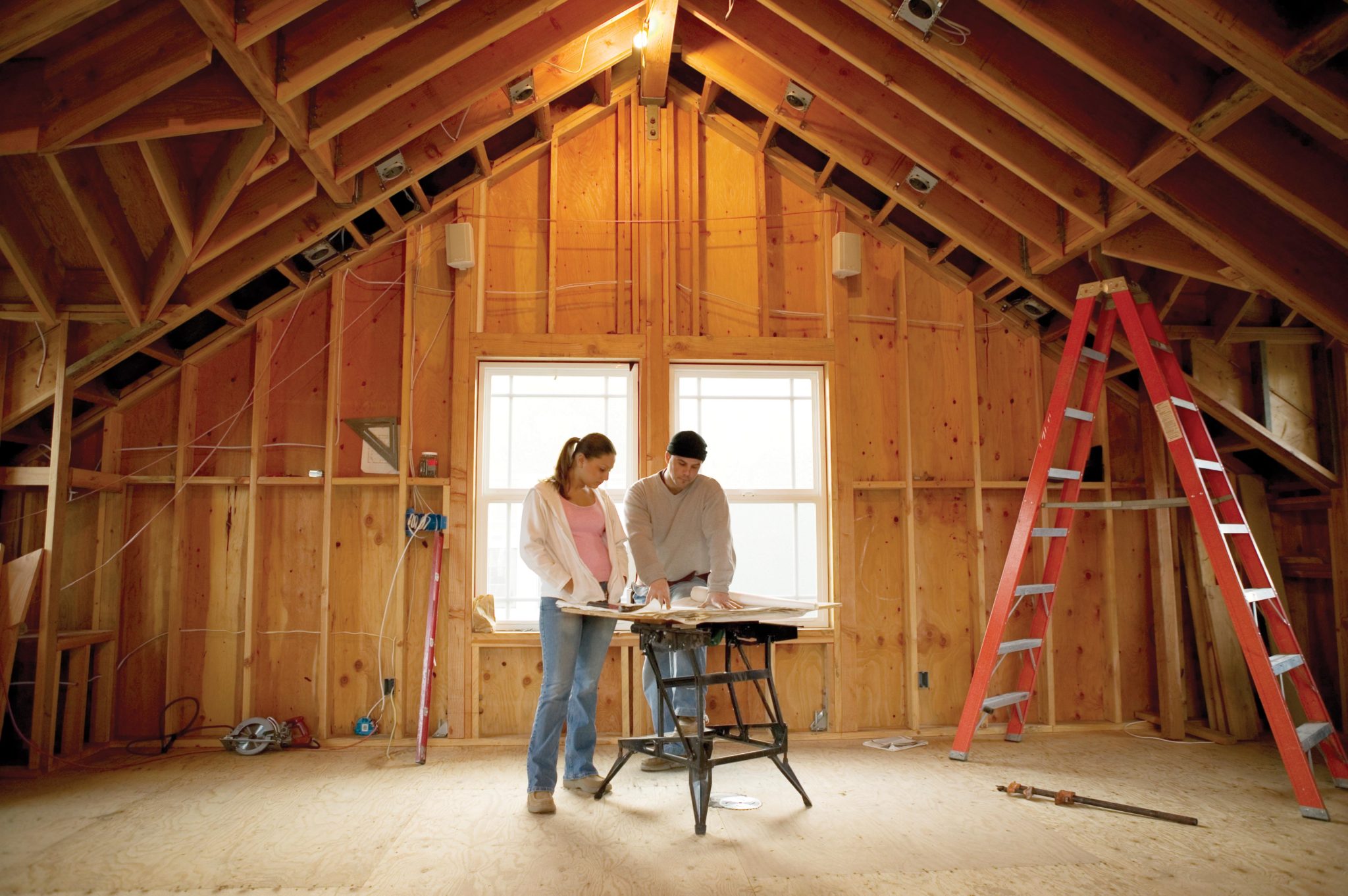 Man and woman looking at blueprints in house under construction
