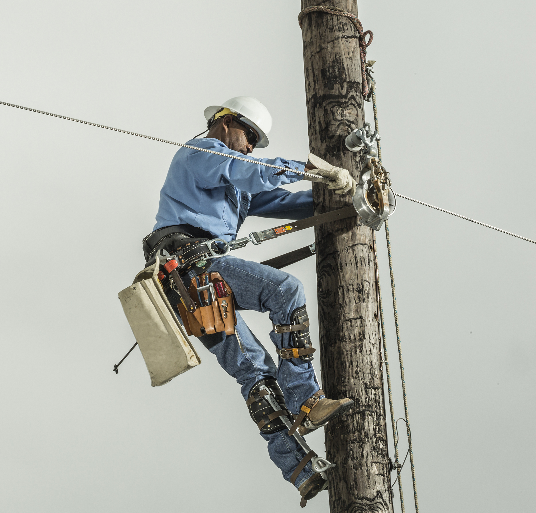 a line worker climbs a utility pole
