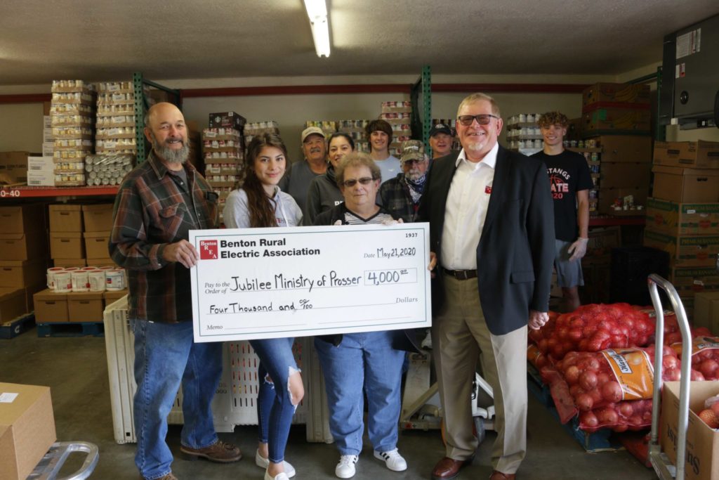 Jubilee Ministries Food Bank volunteers accept a check for $4,000 from Benton REA Board President Mike Freepons