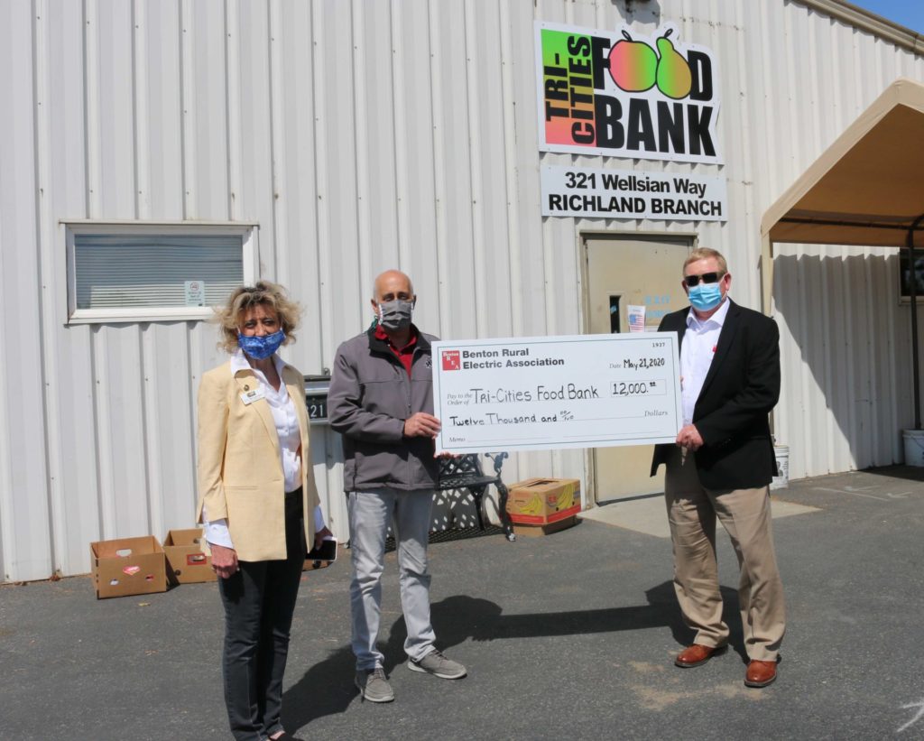 VJ Meadows, executive director, and Howard Rickard, board president of the Tri-Cities Food Bank accept a check for $12,000 from Benton REA Board President Mike Freepons.