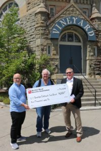 David Hanson, executive director, and Ken Trainor, director of operations for Sunrise Outreach food banks accept a check for $4,000 from Benton REA Board President Mike Freepons
