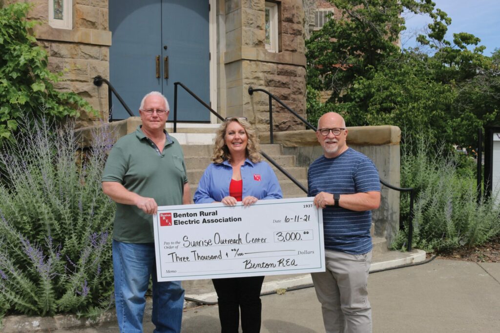 David Hanson, executive director, and Ken Trainor, director of operations for Sunrise Outreach Center food banks accept a check for $3,000 from Benton REA Board President Connie Krull (center).