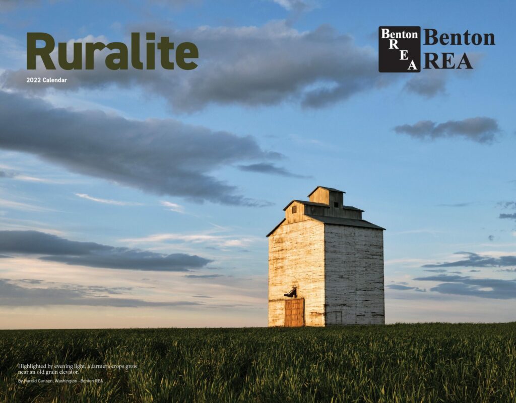 On the cover of the 2022 Ruralite calendar, highlighted by evening light, a farmer’s crops grow near an old grain elevator. PHOTO BY HAROLD CARLSON