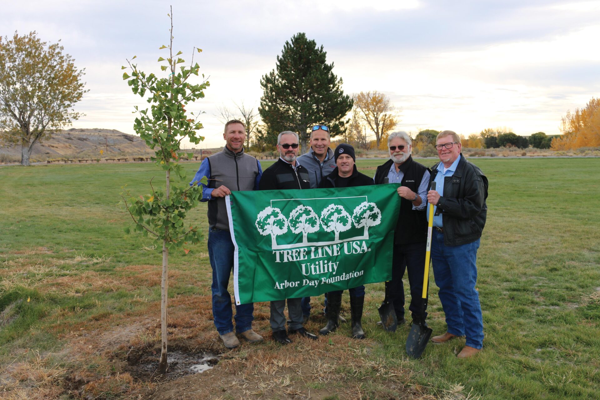 Benton REA employees and trustees hold Tree Line USA flag at Horn Rapids Park in 2021
