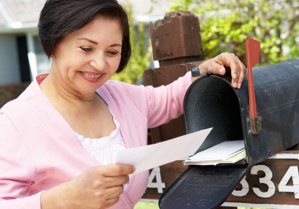 woman smiles as she checks her mail