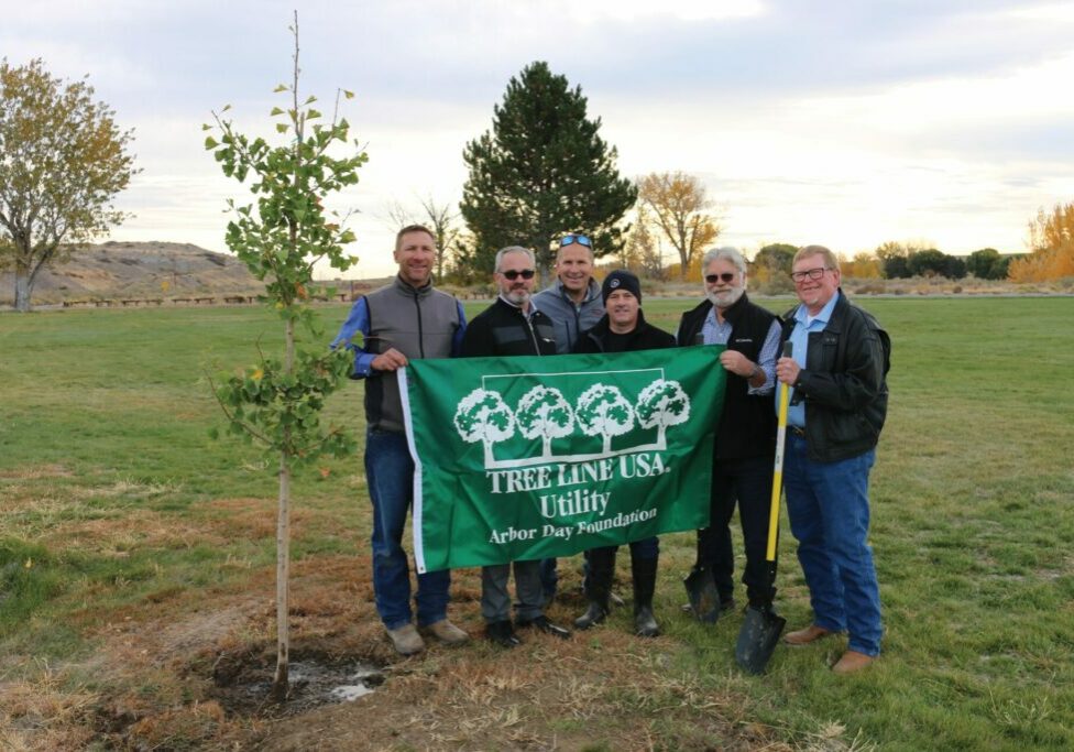 Benton REA employees and trustees hold Tree Line USA flag at Horn Rapids Park in 2021